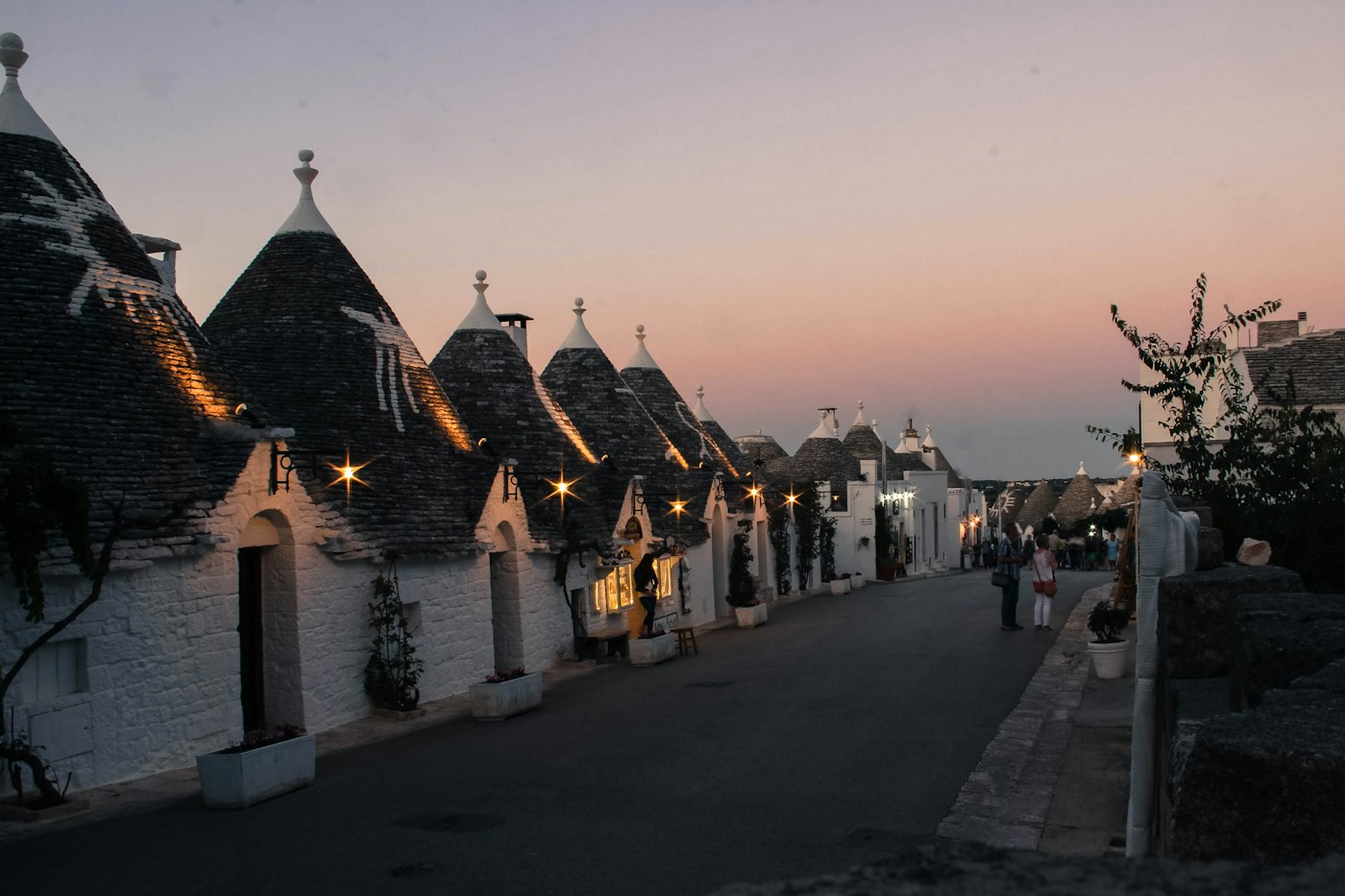 Alberobello në agim, kur rrugicat janë ende të qeta dhe drita e parë ngjyros gurët.
